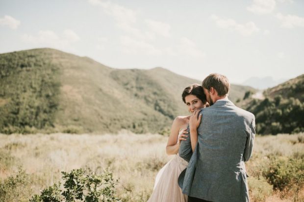 Woman embraces her husband in a field of grass