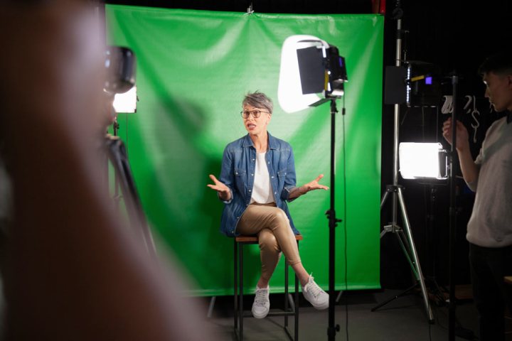 Woman giving an interview while sitting against green screen