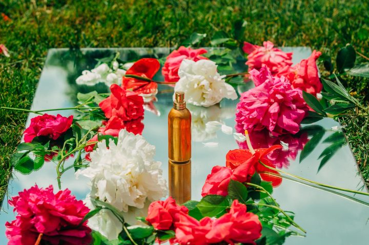 Gold perfume bottle surrounded by pink and white flower bouquets