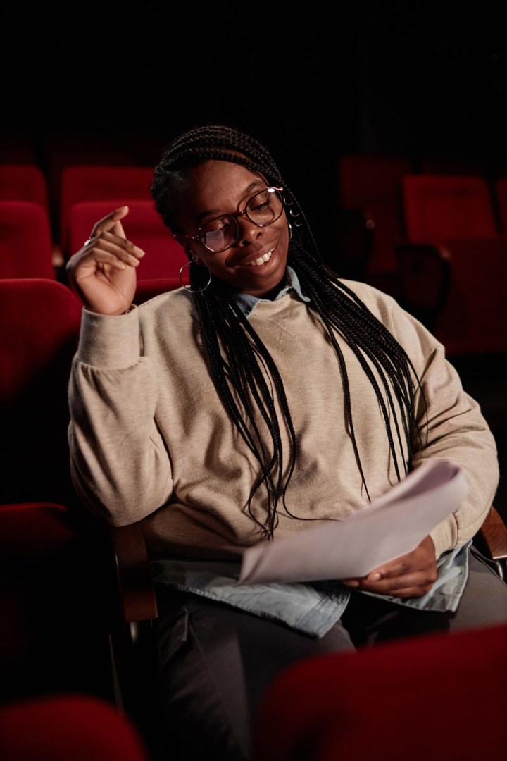 Vertical portrait of smiling African American artist reading script preparing for performance in theater