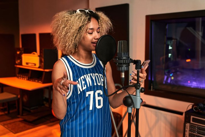 Young Black woman recording a song in studio