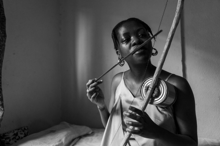 A young black woman showcases her musical talent by playing a traditional South African Xhosa instrument