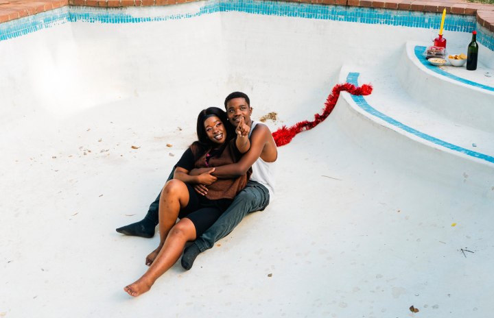 A youthful South African black couple shares a heartwarming moment, while hanging out in an empty pool in their backyard